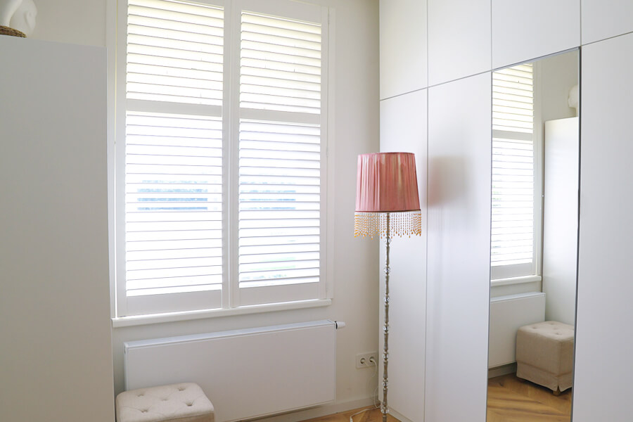 Lichte walk-in-closet met witte shutters